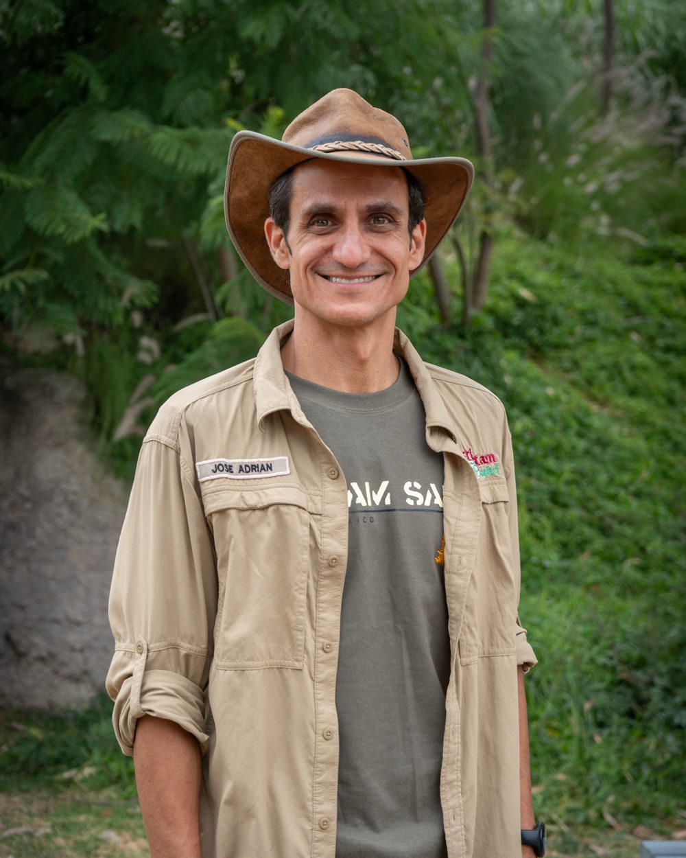 Joseadrián de frente, con sombrero y camisa de campo, en la naturaleza